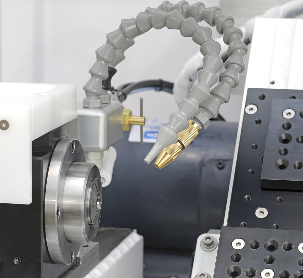 The two coolant nozzles on flexible lines at the Lathe 3 spindle: a plastic liquid-coolant nozzle and a brass-tipped mist nozzle